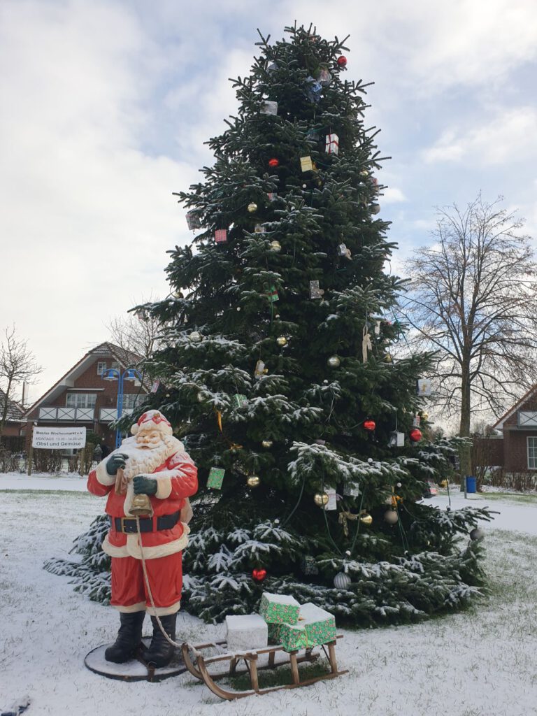 Der Weihnachtsmann steht mit seinem Baum im Schnee