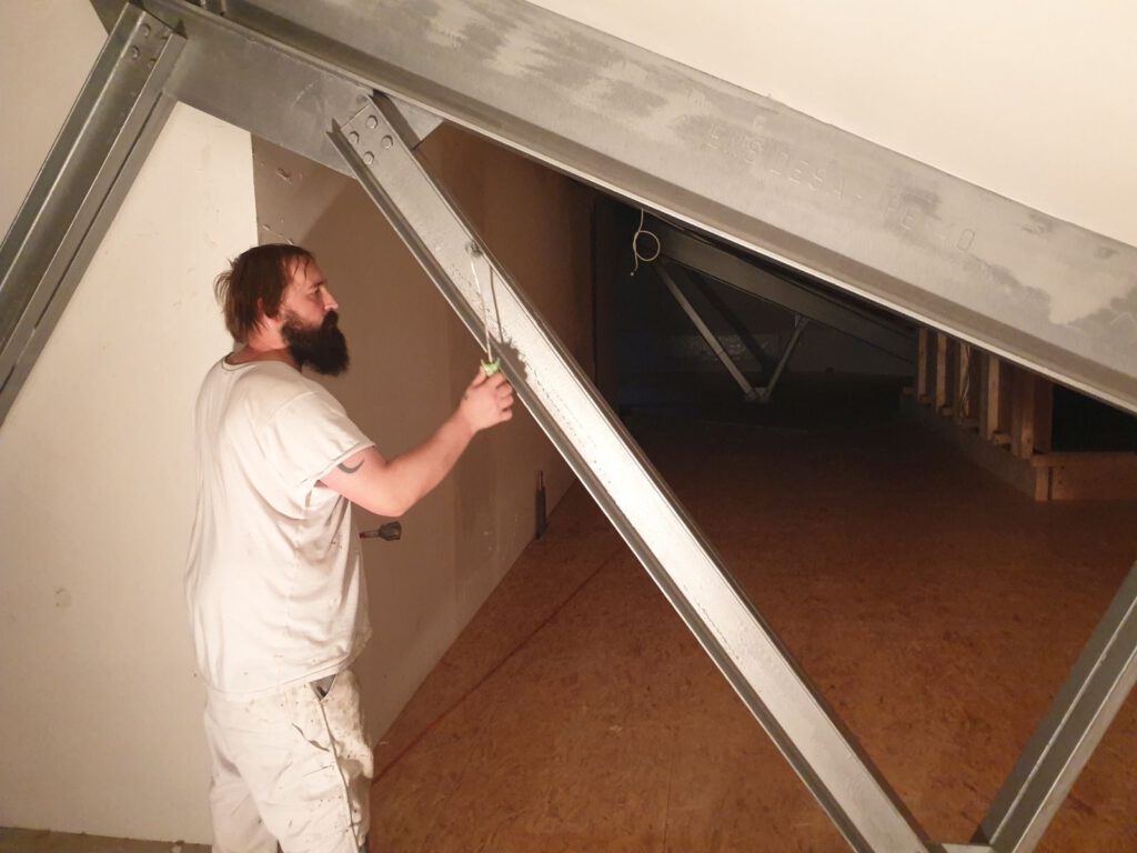 Maler Sascha Kramer schwingt die Farbrolle und streicht die Stahlträger im Obergeschoss