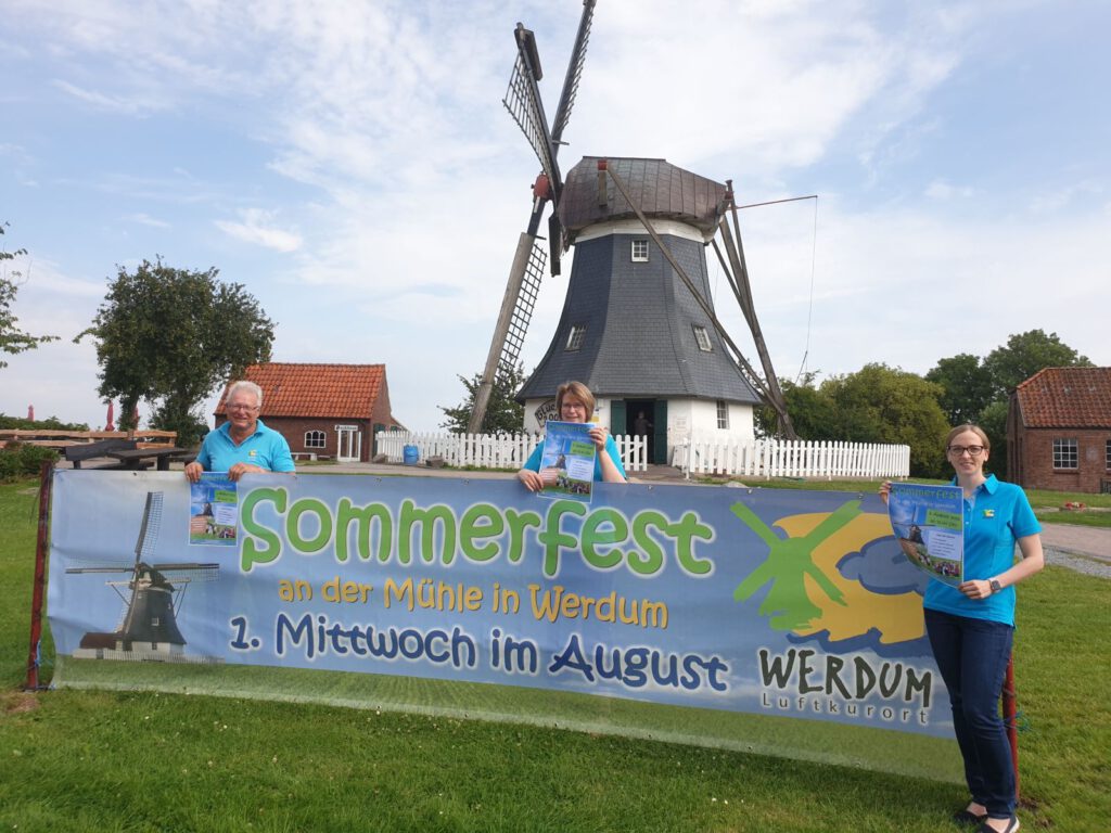 Johann Pieper, Claudia Peters und Sandra Lange präsentieren das "Sommerfestbanner" vor der Mühle