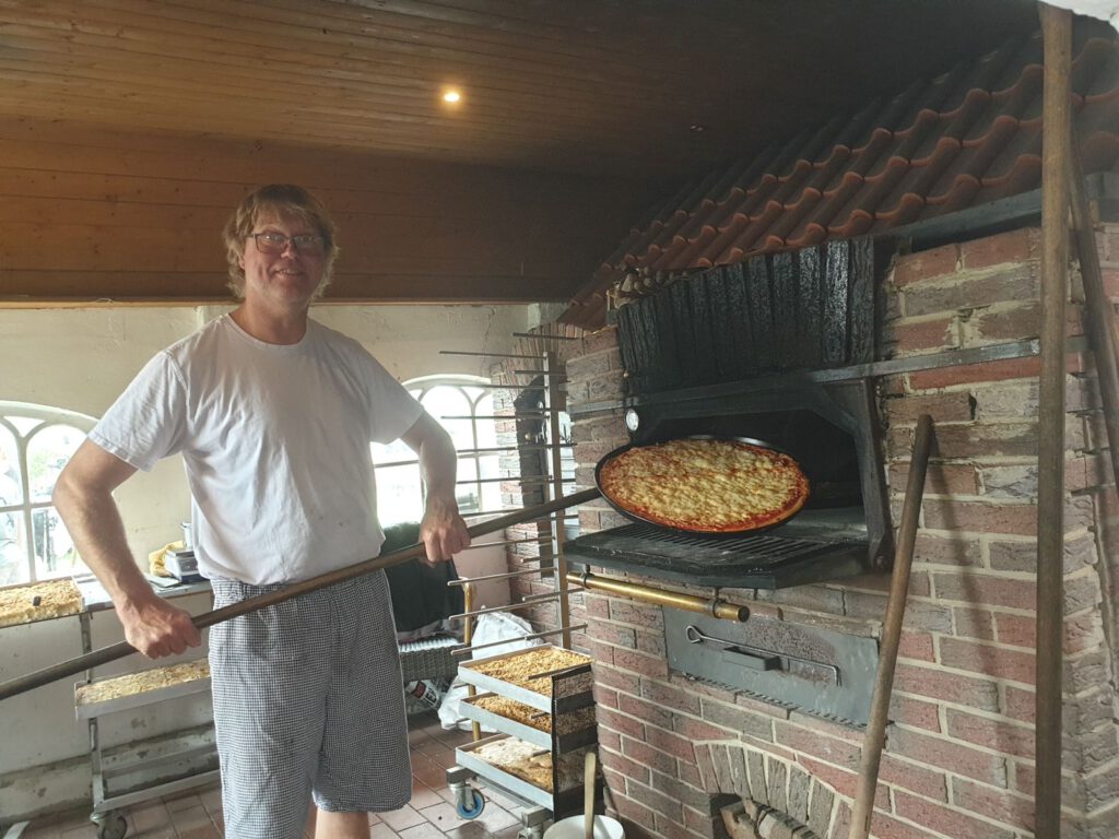 Bäckermeister Jürgen Post holt eine Pizza aus dem Ofen