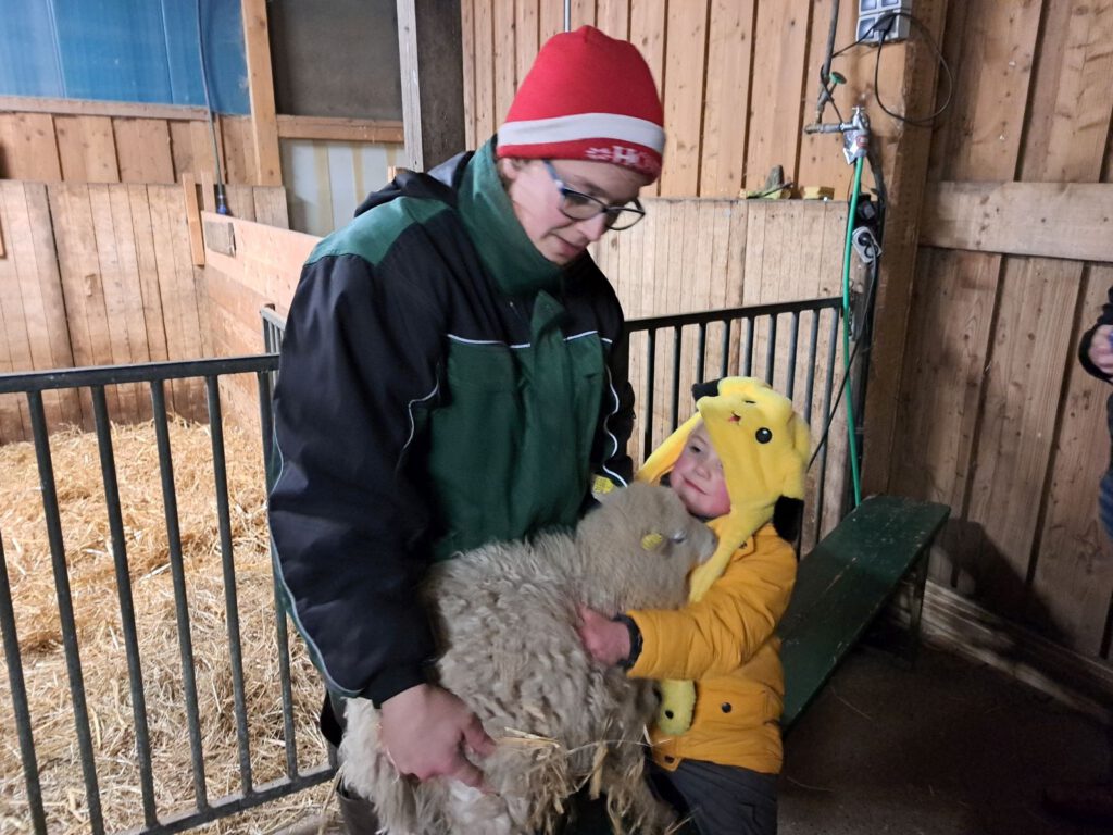 Lenny kuschelt mit dem gerade eingezogene Schaf "Mia" das Mama auf dem Arm hält