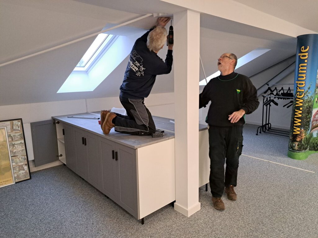 Heinz-Theo Emken und Walter Kammer montieren die Trennwand, die noch tapeziert und gestrichen wird