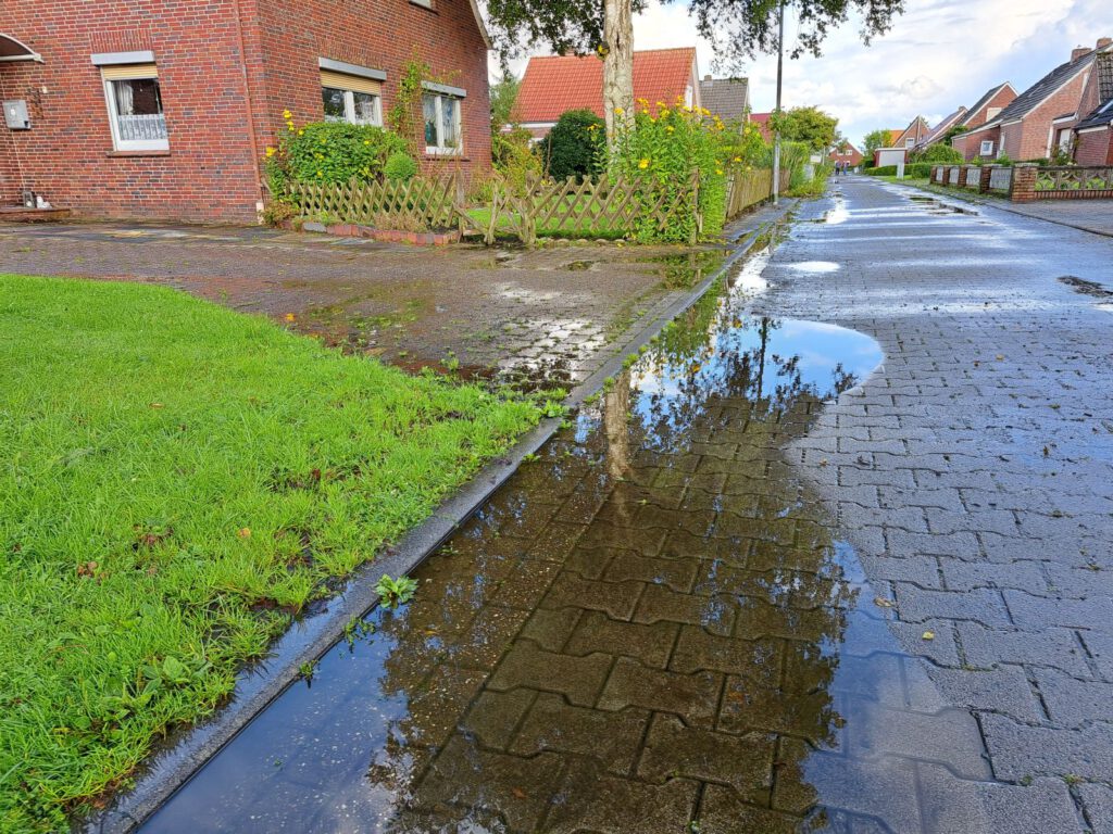 Von Pfützen übersäte Raiffeisenstraße nach dem letzten August-Regen