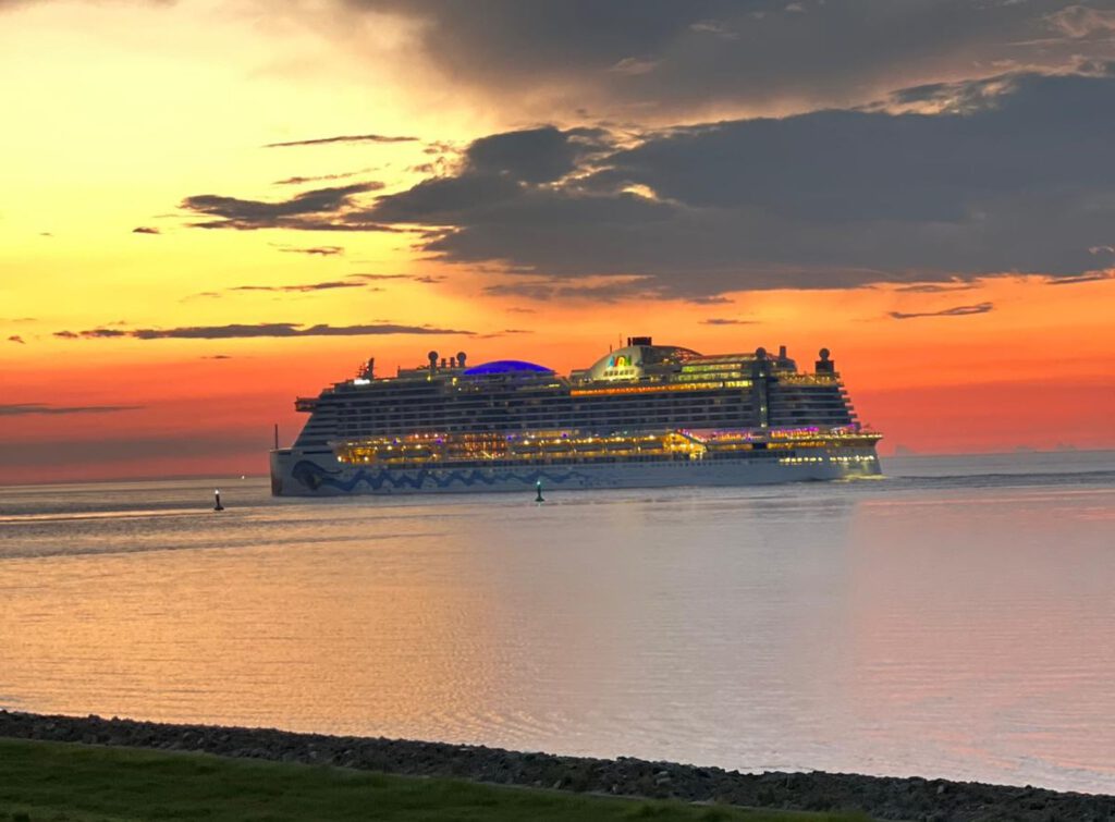 Ein einmaliger Blick auf das auf die Nordsee rausfahrende Kreuzfahrtschiff bei Sonnenuntergang 