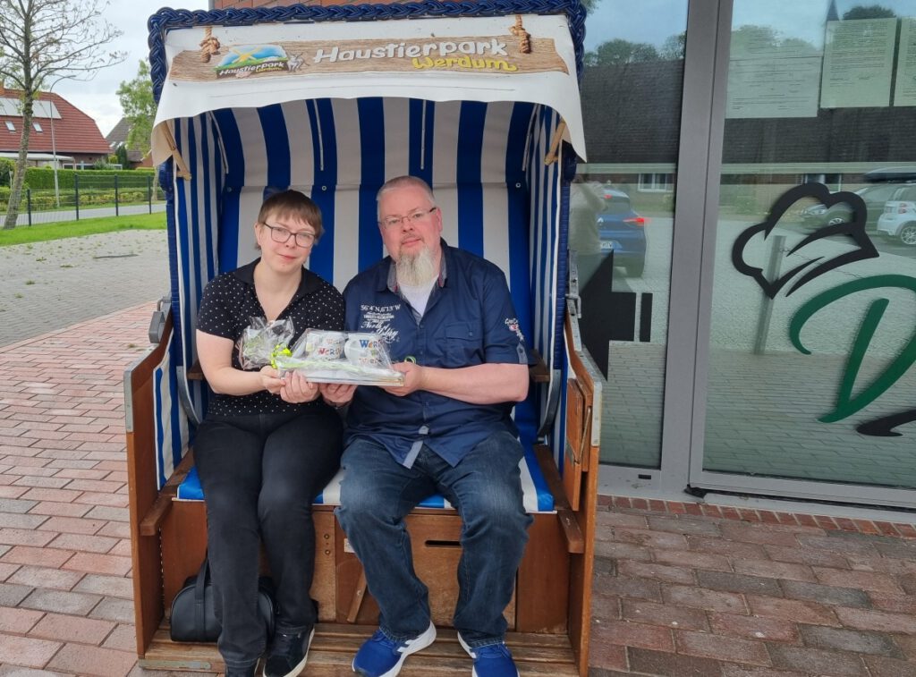 Herr Klauser und Frau Ring  präsentieren im Strandkorb ihr Ehrungsgeschenk.