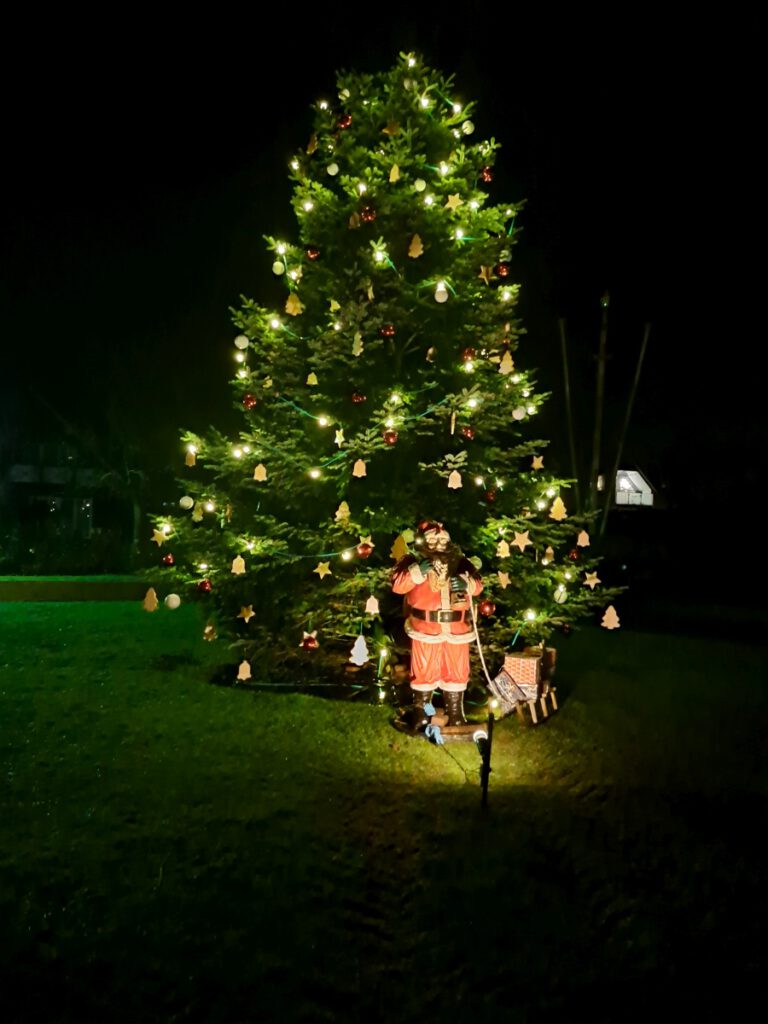 Der große Weihnachtsbaum auf dem Dorfplatz leuchtet unter dem Schutz des Weihnachtsmanns