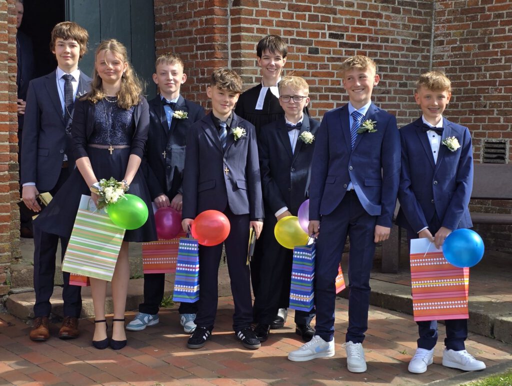 frisch konfirmiert: v.L.: Niklas Kuhnhen, Pheline Schröder, Aaron Sassen, Hanno Ockenga, Hendrik Goldenstein, Timm Suwe und Klaas Meents präsentieren sich stolz mit Pastorin Julia Uelsmann vor der St.-Nikolai-Kirche.